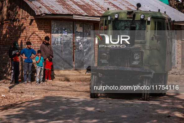 Kashmiri children watch as Indian army vehicles leave the encounter site after killing two militants in Sopore, Jammu and Kashmir, India, on...