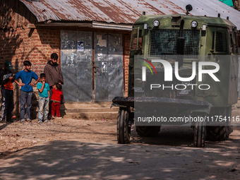 Kashmiri children watch as Indian army vehicles leave the encounter site after killing two militants in Sopore, Jammu and Kashmir, India, on...