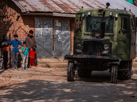 Kashmiri children watch as Indian army vehicles leave the encounter site after killing two militants in Sopore, Jammu and Kashmir, India, on...