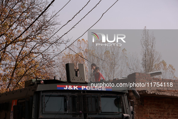 A girl and a boy (siblings) watch the Indian soldiers who engage in an encounter with militants in Sopore, Jammu and Kashmir, India, on Nove...