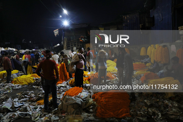 Vendors sell garlands of marigold flowers at a wholesale flower market during dawn on the banks of the river Ganges in Kolkata, India, on No...