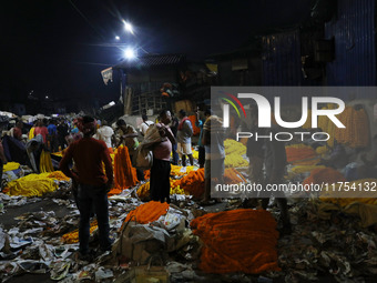 Vendors sell garlands of marigold flowers at a wholesale flower market during dawn on the banks of the river Ganges in Kolkata, India, on No...