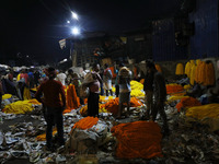 Vendors sell garlands of marigold flowers at a wholesale flower market during dawn on the banks of the river Ganges in Kolkata, India, on No...