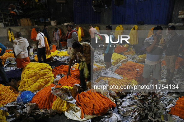 Vendors sell garlands of marigold flowers at a wholesale flower market during dawn on the banks of the river Ganges in Kolkata, India, on No...