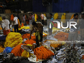 Vendors sell garlands of marigold flowers at a wholesale flower market during dawn on the banks of the river Ganges in Kolkata, India, on No...