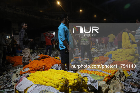 Vendors sell garlands of marigold flowers at a wholesale flower market during dawn on the banks of the river Ganges in Kolkata, India, on No...