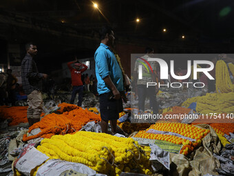 Vendors sell garlands of marigold flowers at a wholesale flower market during dawn on the banks of the river Ganges in Kolkata, India, on No...