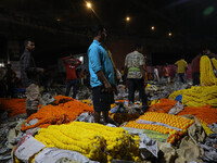 Vendors sell garlands of marigold flowers at a wholesale flower market during dawn on the banks of the river Ganges in Kolkata, India, on No...