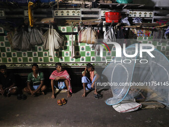 Daily wage workers wait for employment at a wholesale flower market during dawn on the banks of the river Ganges in Kolkata, India, on Novem...