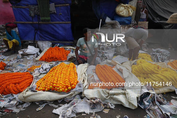 Vendors sell garlands of marigold flowers at a wholesale flower market during dawn on the banks of the river Ganges in Kolkata, India, on No...