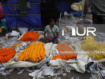 Vendors sell garlands of marigold flowers at a wholesale flower market during dawn on the banks of the river Ganges in Kolkata, India, on No...