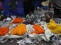 Vendors sell garlands of marigold flowers at a wholesale flower market during dawn on the banks of the river Ganges in Kolkata, India, on No...