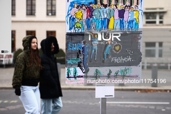 People pass artworks lined up in a four-kilometre-long open-air installation a day ahead of the 35th anniversary of the fall of the Berlin W...