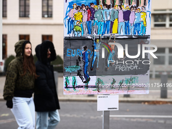 People pass artworks lined up in a four-kilometre-long open-air installation a day ahead of the 35th anniversary of the fall of the Berlin W...