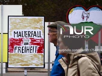 People pass artworks lined up in a four-kilometre-long open-air installation a day ahead of the 35th anniversary of the fall of the Berlin W...