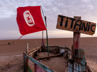 A 'titanic' sign is seen on a wooden boat with Tunisia flag as sun rises over Chott el Djerid salt lake in eastern Sahara, Tunisia on Octobe...