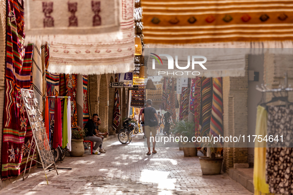 A tourist walks an alee with hand made carpets in souk in Medina of Tozeur in central Tunisia on October 28, 2024. 