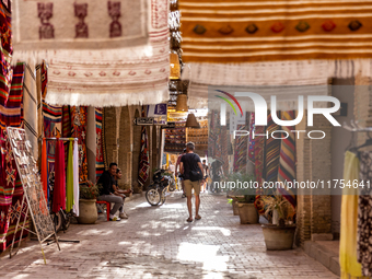 A tourist walks an alee with hand made carpets in souk in Medina of Tozeur in central Tunisia on October 28, 2024. (