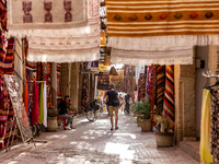 A tourist walks an alee with hand made carpets in souk in Medina of Tozeur in central Tunisia on October 28, 2024. (