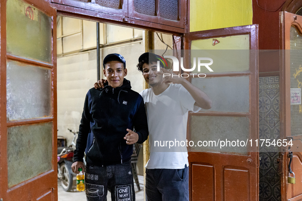 Young men pose to be photographed in a coffee shop in Tozeur in central Tunisia on October 28, 2024. 