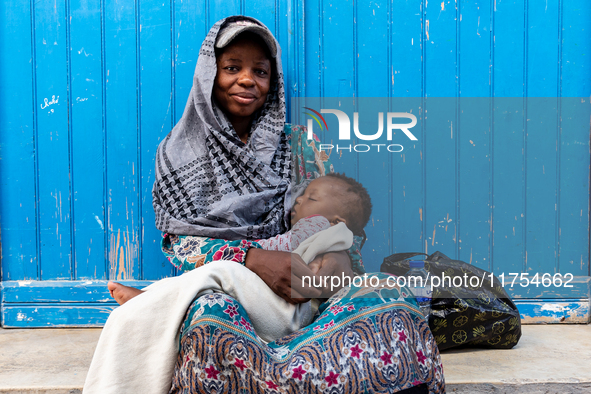 A woman sits with her baby in an Old Town of Soussa, Tunisia on November 2, 2024. 