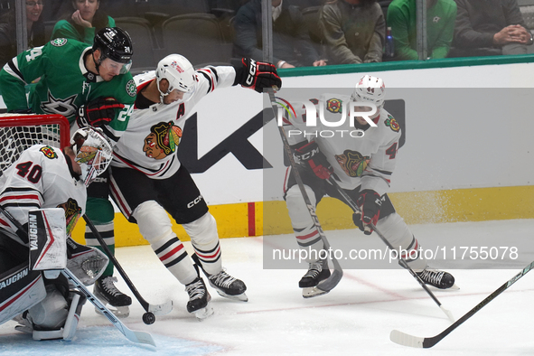 Seth Jones #4 of the Chicago Blackhawks and Roope Hintz #24 of the Dallas Stars battle for the puck while Arvid Soderblom #40, goalkeeper of...