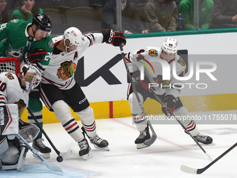 Seth Jones #4 of the Chicago Blackhawks and Roope Hintz #24 of the Dallas Stars battle for the puck while Arvid Soderblom #40, goalkeeper of...