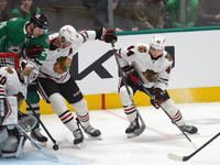 Seth Jones #4 of the Chicago Blackhawks and Roope Hintz #24 of the Dallas Stars battle for the puck while Arvid Soderblom #40, goalkeeper of...