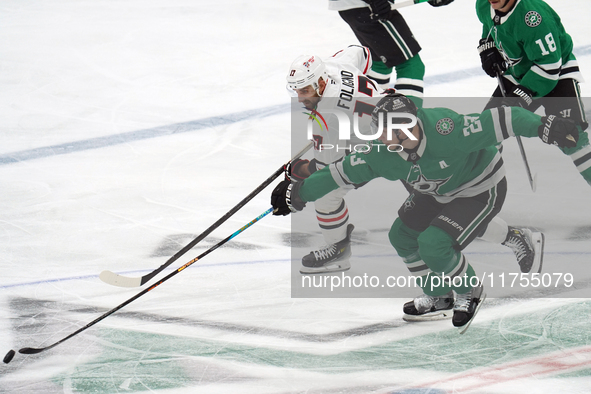 Esa Lindell #23 of the Dallas Stars and Nick Foligno #17 of the Chicago Blackhawks skate, battling for the puck during the NHL match at Amer...