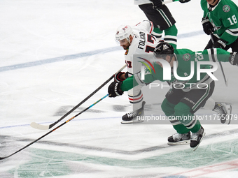 Esa Lindell #23 of the Dallas Stars and Nick Foligno #17 of the Chicago Blackhawks skate, battling for the puck during the NHL match at Amer...