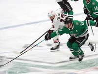 Esa Lindell #23 of the Dallas Stars and Nick Foligno #17 of the Chicago Blackhawks skate, battling for the puck during the NHL match at Amer...