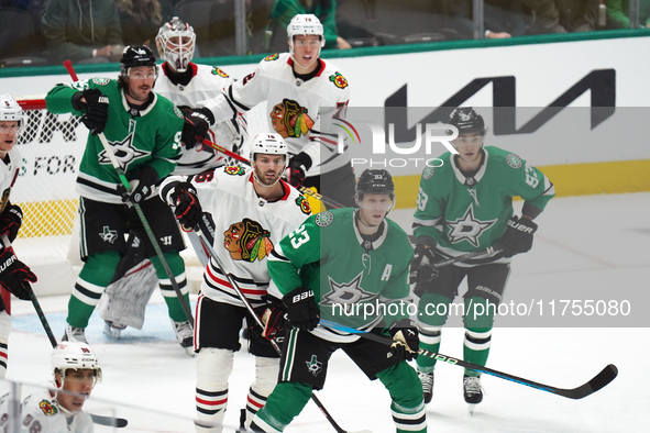 Esa Lindell #23 of the Dallas Stars and Jason Dickinson #16 of the Chicago Blackhawks play during the NHL match at American Airlines Center...