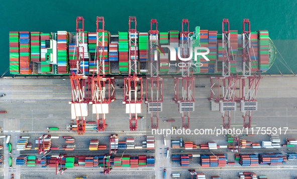 A global super-class container ship unloads containers at the Qianwan container terminal of Qingdao Port in Qingdao, China, on November 8, 2...