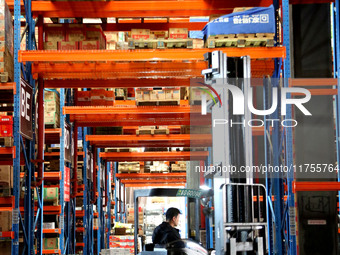 A staff member transfers goods at an e-commerce logistics warehouse in Lianyun district, Lianyungang, China, on November 9, 2024. (