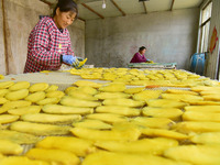 A farmer nets dried, sliced sweet potatoes for baking in Zaozhuang, China, on November 9, 2024. (