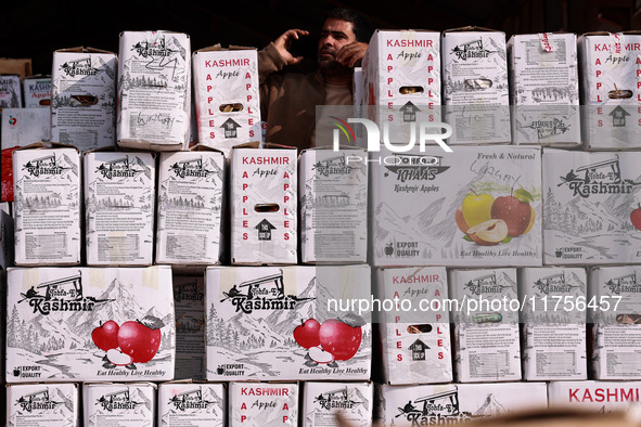 A trader speaks on his phone as boxes of apples are kept for sale at Asia's second largest fruit market in Sopore, Jammu and Kashmir, India,...