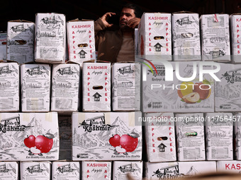 A trader speaks on his phone as boxes of apples are kept for sale at Asia's second largest fruit market in Sopore, Jammu and Kashmir, India,...