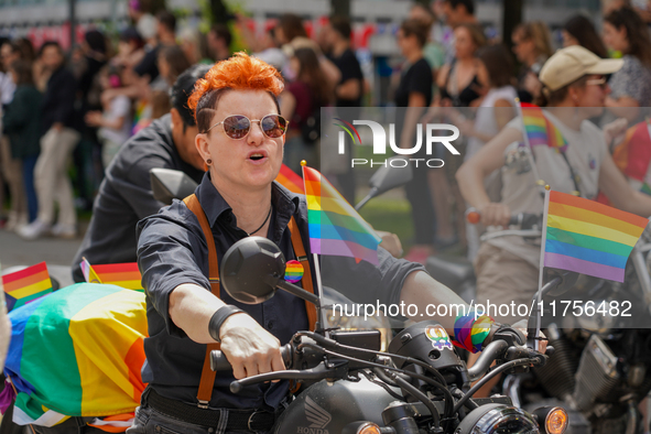 The image shows a scene from a Christopher Street Day (CSD) parade in Munich, Germany, on June 22, 2024, with a participant on a motorcycle...