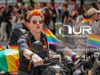 The image shows a scene from a Christopher Street Day (CSD) parade in Munich, Germany, on June 22, 2024, with a participant on a motorcycle...