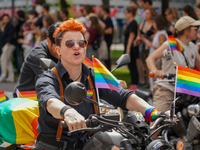 The image shows a scene from a Christopher Street Day (CSD) parade in Munich, Germany, on June 22, 2024, with a participant on a motorcycle...