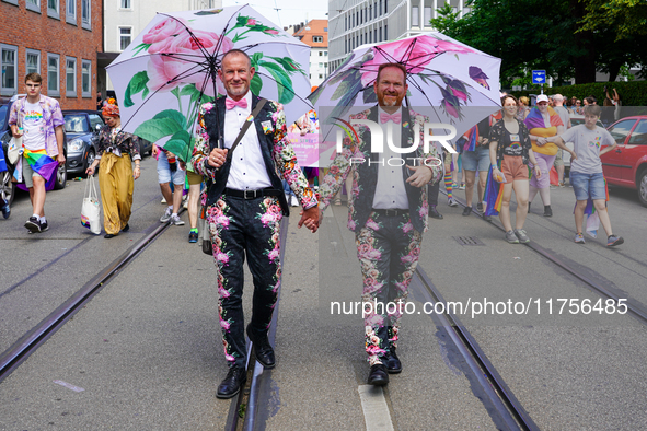 The image shows a gay couple walking hand in hand during the Christopher Street Day (CSD) parade in Munich, Germany, on June 22, 2024. They...