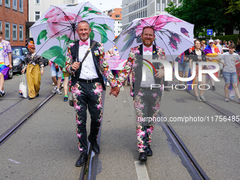 The image shows a gay couple walking hand in hand during the Christopher Street Day (CSD) parade in Munich, Germany, on June 22, 2024. They...