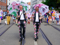 The image shows a gay couple walking hand in hand during the Christopher Street Day (CSD) parade in Munich, Germany, on June 22, 2024. They...