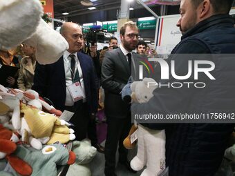 France's Minister for the Economy, Finance and Industry, Antoine Armand, examines plush toys at the ''Les Petites Maries'' brand's stand as...