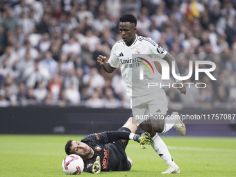 Vinicius Jr of Real Madrid and Sergio Herrera of Osasuna are in action during the La Liga 2024/25 match between Real Madrid and Osasuna at S...