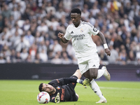 Vinicius Jr of Real Madrid and Sergio Herrera of Osasuna are in action during the La Liga 2024/25 match between Real Madrid and Osasuna at S...