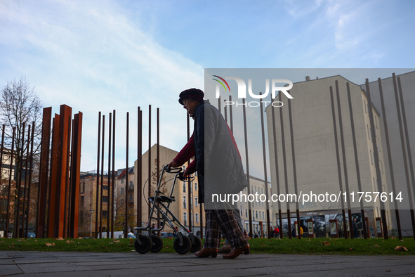 People walk by Berlin Wall remains at Berlin Wall Memorial during the 35th anniversary of the fall of the Berlin Wall. Berlin, Germany on 9...