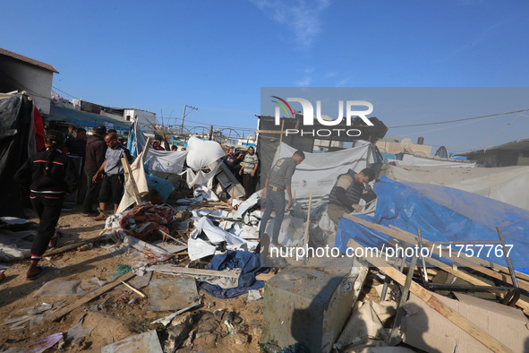 Palestinians inspect the site of an Israeli strike on a tent housing displaced people at Al-Aqsa Martyrs Hospital in Deir Al-Balah, in the c...