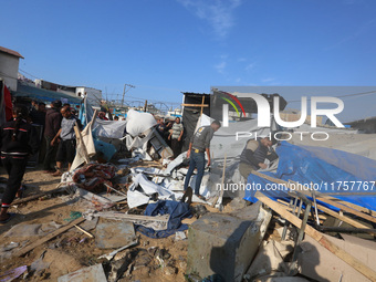 Palestinians inspect the site of an Israeli strike on a tent housing displaced people at Al-Aqsa Martyrs Hospital in Deir Al-Balah, in the c...