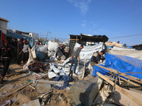 Palestinians inspect the site of an Israeli strike on a tent housing displaced people at Al-Aqsa Martyrs Hospital in Deir Al-Balah, in the c...